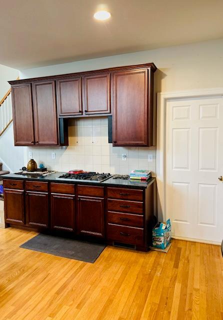 kitchen with backsplash, light hardwood / wood-style floors, and stainless steel gas cooktop