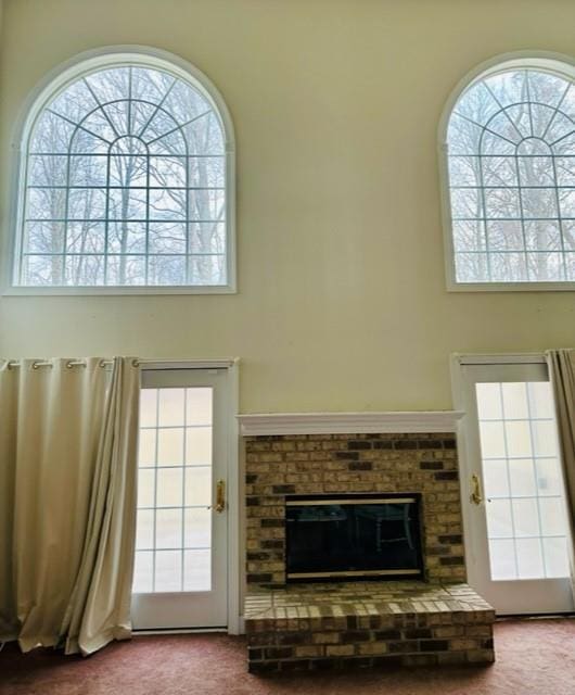 carpeted living room featuring plenty of natural light and a brick fireplace