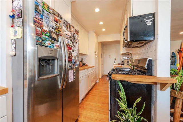 kitchen featuring white cabinetry, butcher block countertops, backsplash, light hardwood / wood-style floors, and appliances with stainless steel finishes