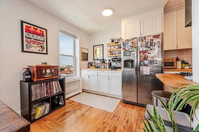 kitchen with white cabinets, light wood-type flooring, stainless steel fridge with ice dispenser, and backsplash