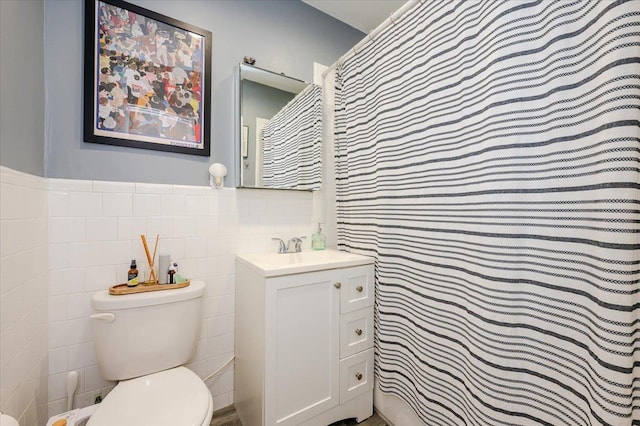 bathroom featuring vanity, toilet, and tile walls