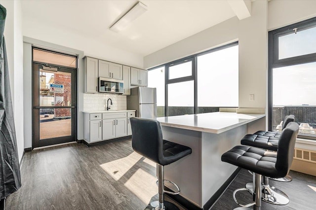 kitchen featuring a breakfast bar, dark wood-type flooring, sink, kitchen peninsula, and stainless steel appliances