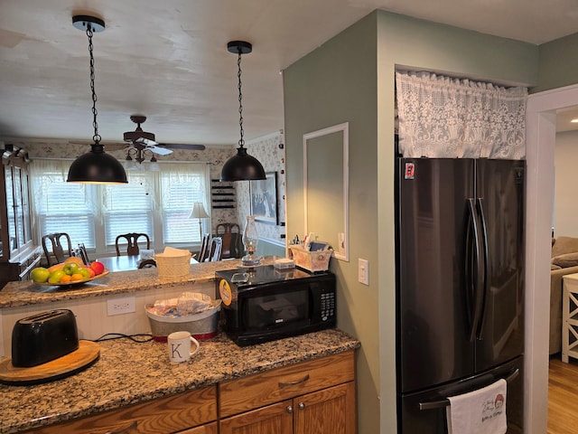 kitchen with light stone counters, ceiling fan, pendant lighting, light hardwood / wood-style floors, and fridge