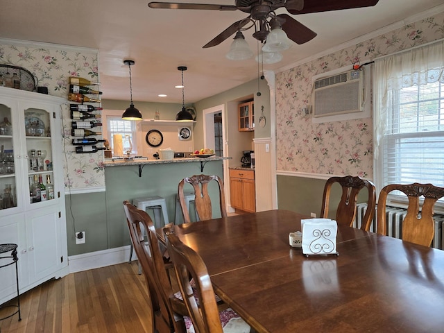 dining area with an AC wall unit, a wealth of natural light, dark hardwood / wood-style flooring, and crown molding