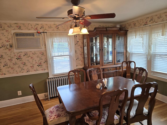 dining room with a wall mounted AC, wood-type flooring, radiator, and crown molding