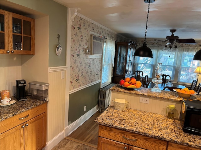 kitchen featuring stone counters, crown molding, dark hardwood / wood-style flooring, and decorative light fixtures