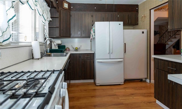 kitchen featuring dark brown cabinetry, white appliances, a sink, light countertops, and open shelves