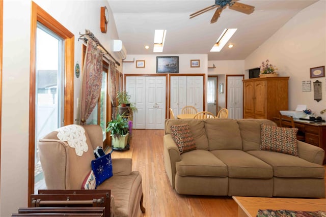 living room featuring lofted ceiling with skylight, ceiling fan, and light hardwood / wood-style floors