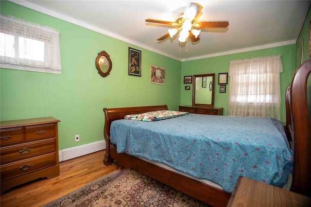 bedroom featuring multiple windows, light hardwood / wood-style floors, ceiling fan, and ornamental molding