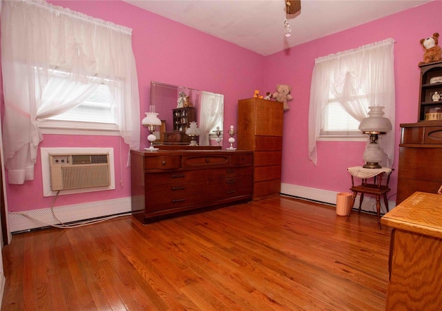 interior space with hardwood / wood-style floors, baseboard heating, and a wall unit AC