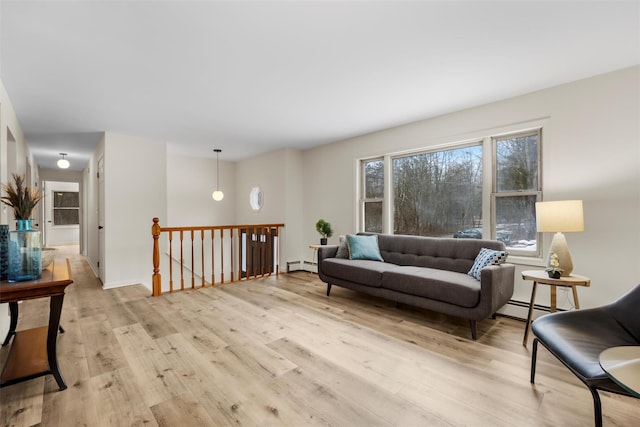 living area featuring baseboard heating, a wealth of natural light, and light wood-type flooring