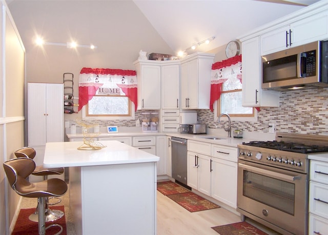 kitchen with a center island, sink, appliances with stainless steel finishes, tasteful backsplash, and white cabinetry