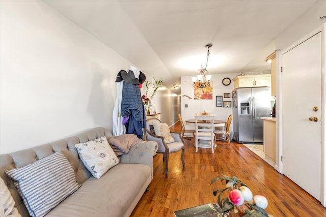 living room featuring a notable chandelier, vaulted ceiling, and light hardwood / wood-style flooring