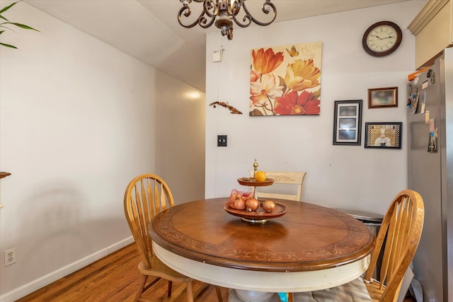 dining space featuring hardwood / wood-style flooring and an inviting chandelier