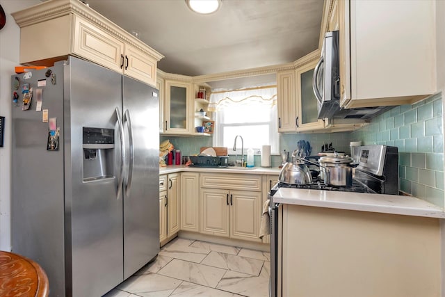 kitchen featuring cream cabinetry, appliances with stainless steel finishes, decorative backsplash, and sink