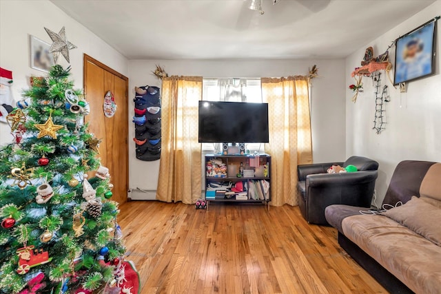 living room with ceiling fan, a baseboard heating unit, and light wood-type flooring