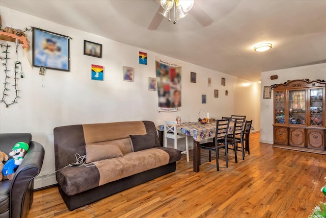 living room with ceiling fan, light wood-type flooring, and baseboard heating