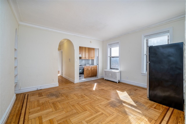 unfurnished living room with radiator, light parquet floors, and ornamental molding