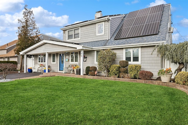 view of front of house with covered porch, a front yard, and solar panels