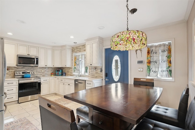 kitchen featuring pendant lighting, crown molding, sink, appliances with stainless steel finishes, and tasteful backsplash