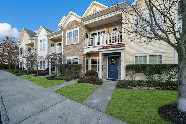 townhome / multi-family property with a balcony and a front yard