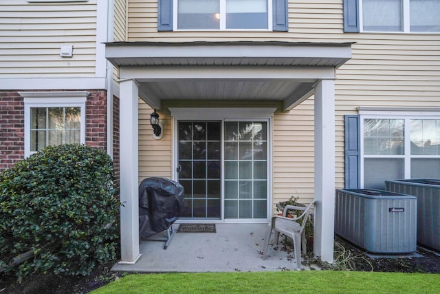 view of exterior entry with a patio area and central air condition unit