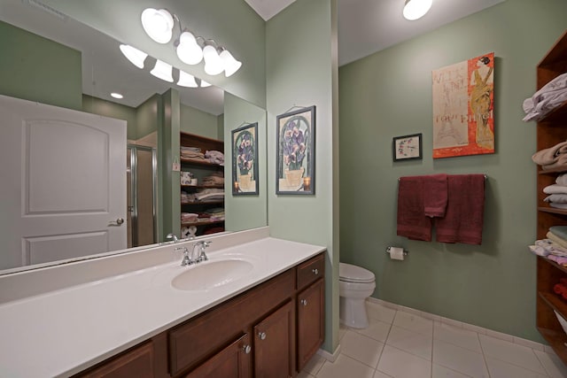 bathroom featuring tile patterned flooring, vanity, toilet, and a shower with shower door