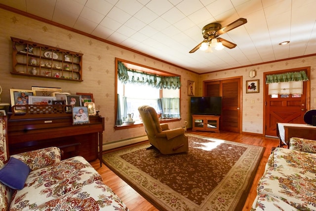 living room with light hardwood / wood-style floors, baseboard heating, crown molding, and ceiling fan