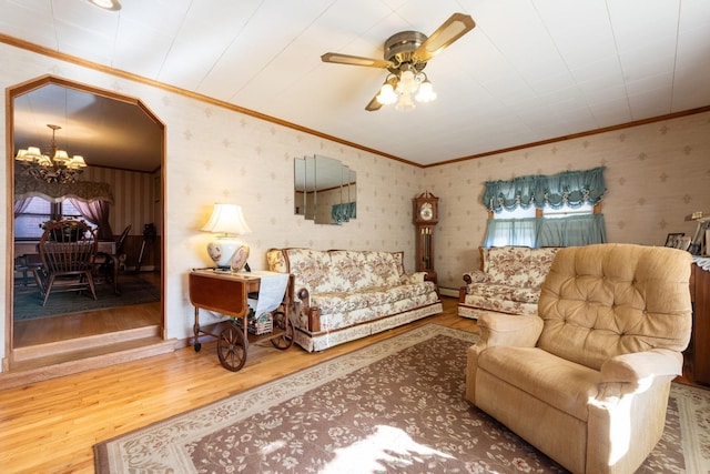 living room with wood-type flooring, ceiling fan with notable chandelier, and ornamental molding