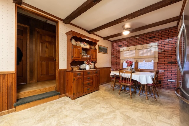 dining space featuring beam ceiling and wooden walls