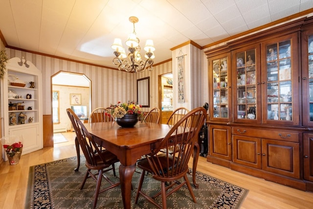 dining space featuring a notable chandelier, light hardwood / wood-style floors, built in features, and crown molding