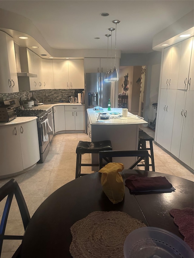 kitchen featuring a center island, tasteful backsplash, decorative light fixtures, stainless steel appliances, and extractor fan