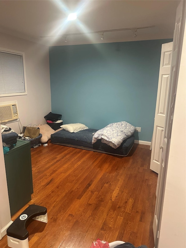 bedroom featuring hardwood / wood-style floors, a wall unit AC, and track lighting