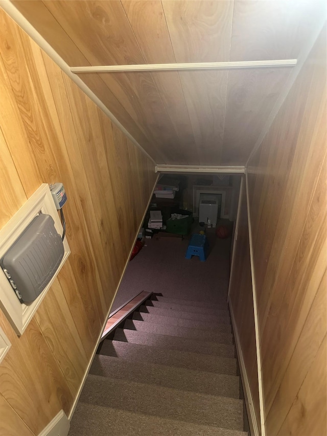 stairs with wood walls, carpet floors, and vaulted ceiling