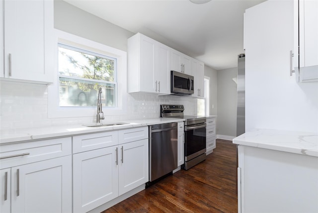 kitchen with light stone countertops, sink, dark hardwood / wood-style floors, white cabinets, and appliances with stainless steel finishes