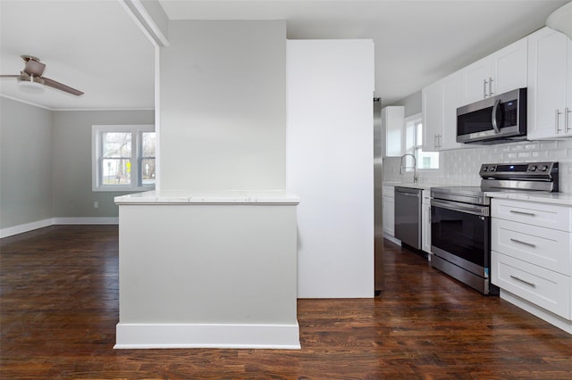 kitchen with white cabinets, decorative backsplash, ceiling fan, appliances with stainless steel finishes, and dark hardwood / wood-style flooring