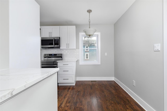 kitchen with light stone countertops, appliances with stainless steel finishes, dark hardwood / wood-style flooring, white cabinetry, and hanging light fixtures