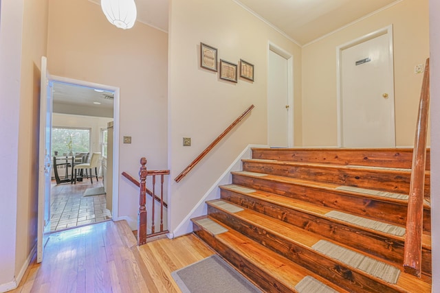 stairs with hardwood / wood-style flooring and ornamental molding