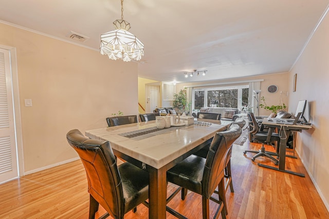 dining space with light wood-type flooring, ornamental molding, and a chandelier