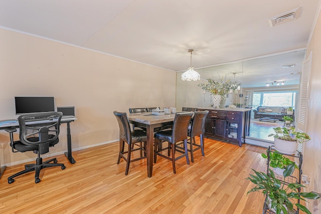 dining space featuring light hardwood / wood-style floors, ornamental molding, and a baseboard radiator