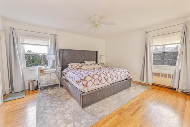 bedroom with hardwood / wood-style floors, radiator heating unit, and ceiling fan