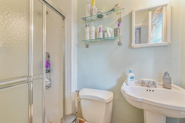 bathroom with toilet, a shower with door, and sink