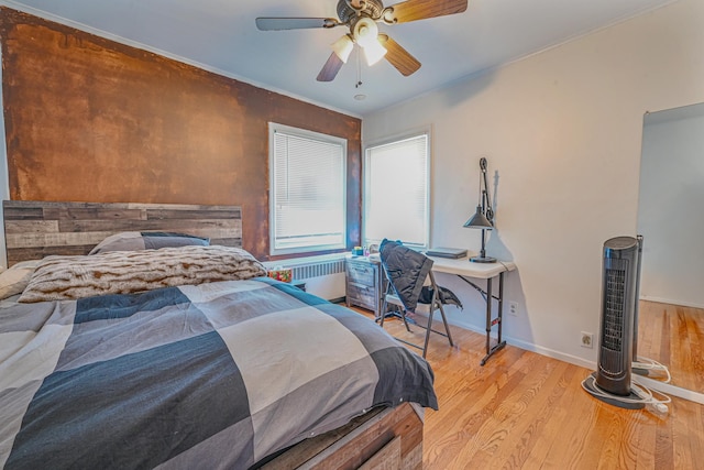 bedroom featuring ceiling fan, light hardwood / wood-style floors, radiator heating unit, and ornamental molding