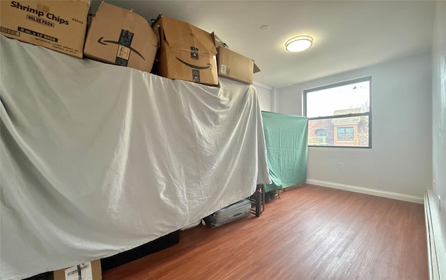 unfurnished bedroom featuring hardwood / wood-style floors and baseboard heating