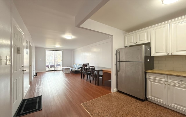 kitchen with backsplash, stainless steel refrigerator, hardwood / wood-style floors, and white cabinets