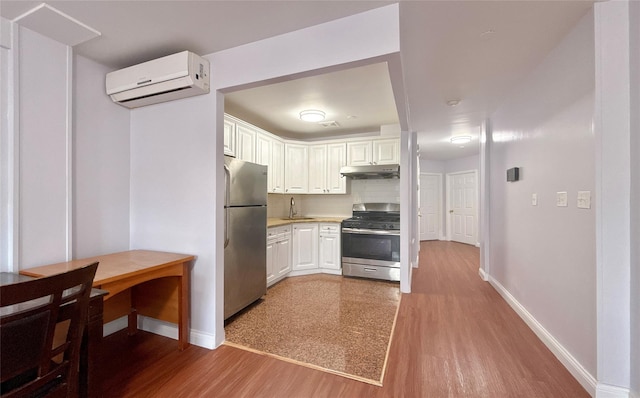 kitchen with tasteful backsplash, white cabinetry, stainless steel appliances, and a wall mounted air conditioner