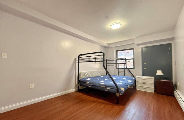 unfurnished bedroom featuring wood-type flooring and a baseboard radiator