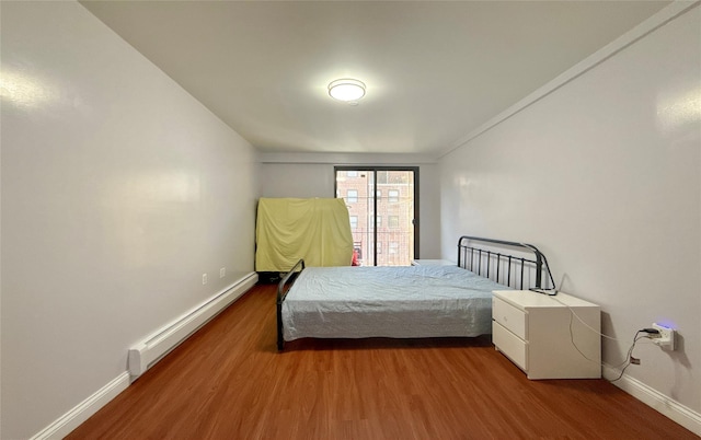 bedroom featuring baseboard heating and hardwood / wood-style flooring