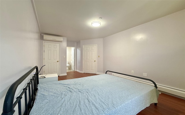 bedroom with a wall mounted AC, ensuite bathroom, and dark hardwood / wood-style floors