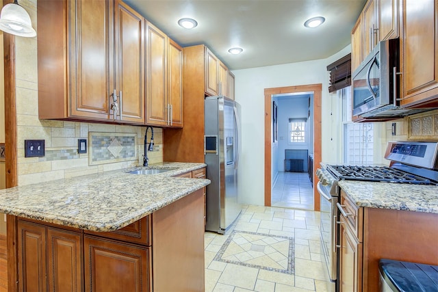 kitchen featuring light stone countertops, sink, pendant lighting, decorative backsplash, and appliances with stainless steel finishes